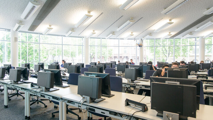 Computerbereich der Abteilung Volkswirtschaftslehre Ein Raum mit vielen Rechnern auf mehreren Tischreihen. Im Hintergrund eine Fensterfront.