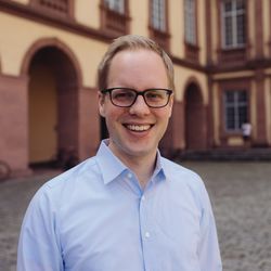 Jens Brandenburg hat kurze blonde Haare und eine Brille. Er trägt ein hellblaues Hemd.
